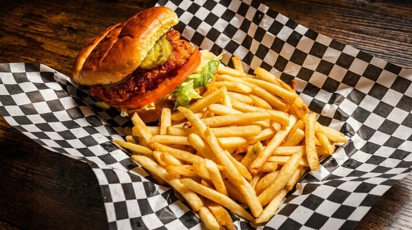Crispy chicken sandwich with pickles, tomato, and lettuce, served with a side of golden fries.